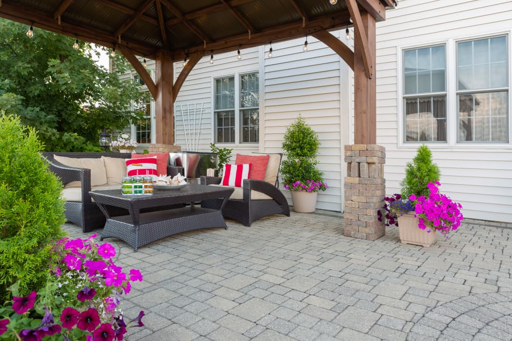 Brussel block design pavers on an exterior patio and summer living space with a covered gazebo, colourful petunias and comfortable seating